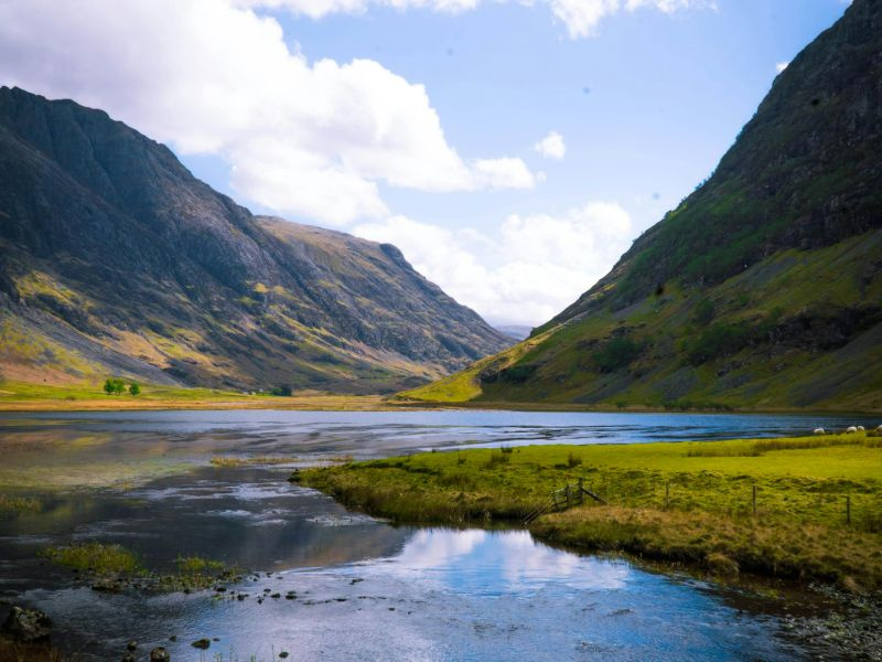 Calm water next to two large hills.