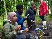 Young people enjoying food around a campfire - copyright the Seven Lochs Wetland Park